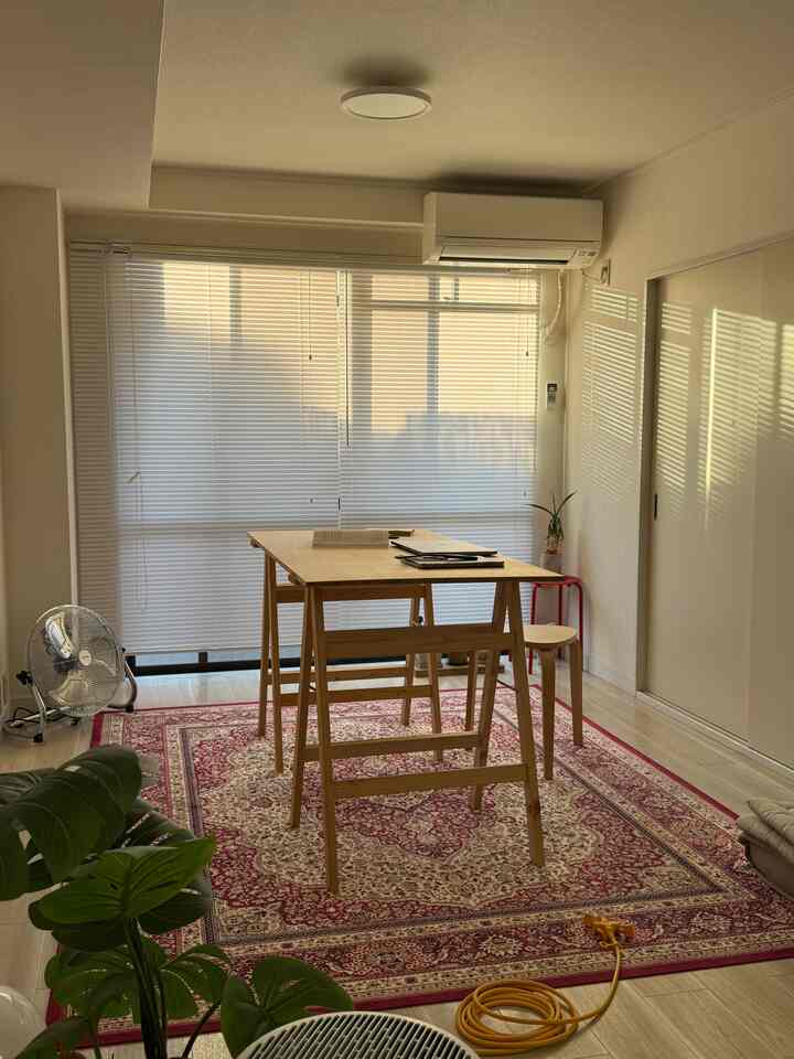 A bright and clean Mid-Century Modern room in white and red tones featuring a wooden table and stool centered in the space