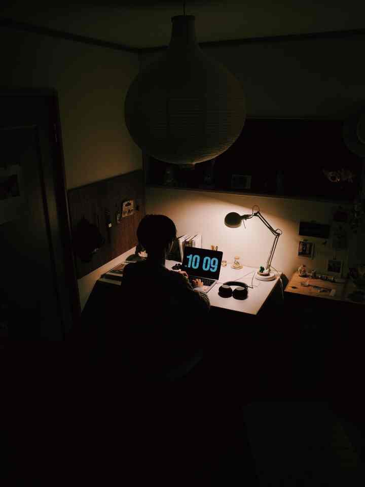 暗い夜の空間にホワイトデスクとペンダントライトが配置された6畳の一人暮らし用寝室兼書斎のインテリア