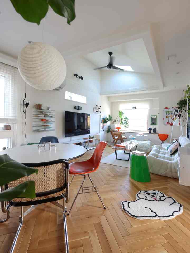 白い壁と木目調の床が印象的な明るく広いリビング、丸いダイニングテーブルと様々な椅子、快適なソファが配置された北欧風のインテリア