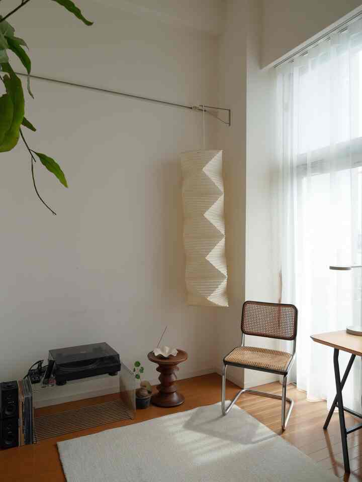 白と木目調が調和したリビング、自然素材のスツールとアームチェアが配置されたシンプルな空間