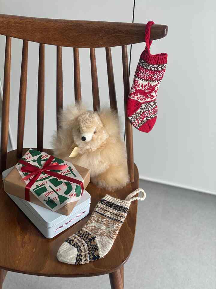 Red and brown toned chair featuring a pet-like plush and Christmas stockings, creating a cozy home party vibe