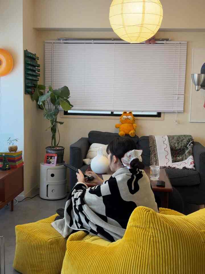 白と黄色の色調が印象的な12畳のリビング、LOOSYソファとブランケットが配置された雰囲気のあるインテリア