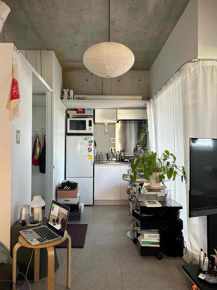 White and gray studio apartment kitchen featuring simple furniture and accessories with a clean interior atmosphere