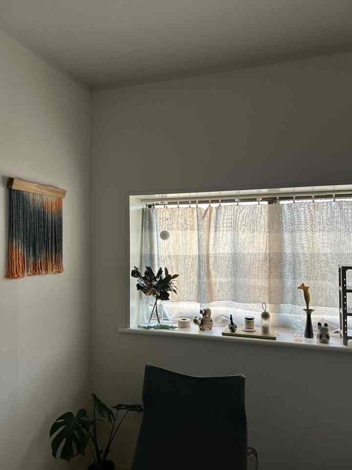 A studio apartment with white and navy tones featuring curtains and small interior accessories on the window ledge, creating a warm natural atmosphere