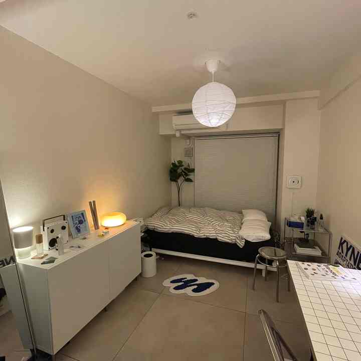White and gray toned studio bedroom featuring a bed, point rug, and stool in a cozy space