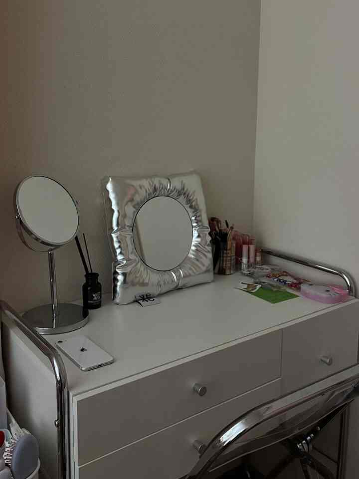 白を基調とした狭いパウダールーム、ミッドセンチュリーモダンの化粧台と透明アクリル椅子が配置されたシンプルで洗練されたインテリア