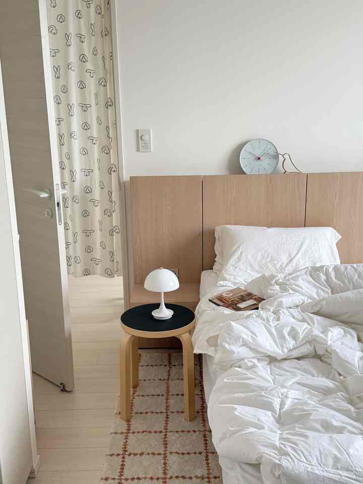White and beige toned bedroom featuring a neat bed and a simple stool creating a cozy atmosphere