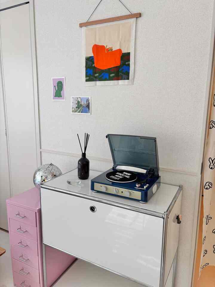 白とクロムが特徴的なリビングに、レトロなレコードプレーヤーとプレミアムディフューザーが置かれた洗練された空間