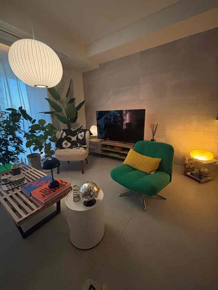 Living room in white and green tones featuring Mid-Century Modern armchairs and pendant lighting with cozy atmosphere