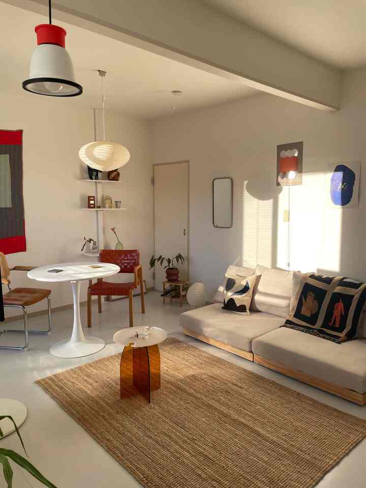 白と茶色のトーンでまとめられたモダンな北欧リビング、ソファと丸いダイニングテーブルが配置された温かみのある空間