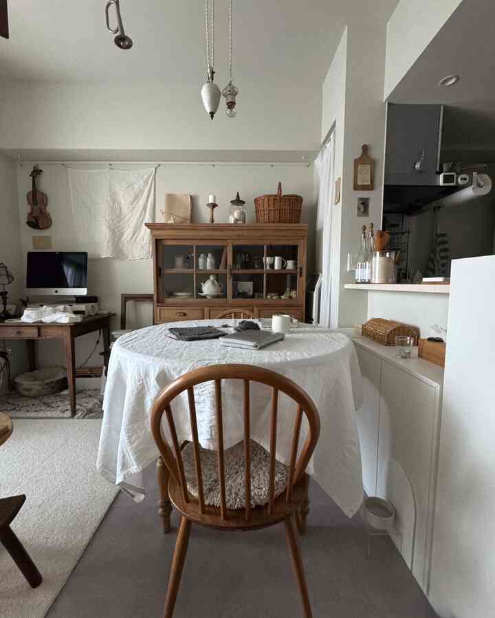 白い壁とナチュラルな木製家具が調和した1LDKのダイニングルーム、丸いテーブルと椅子が配置された温かみのある空間