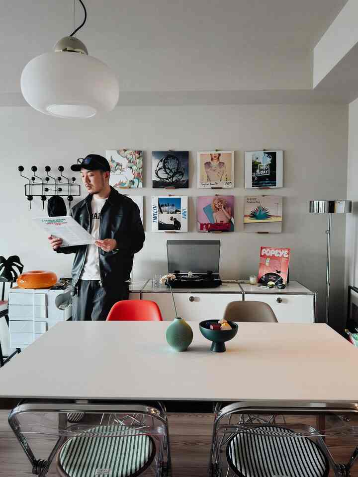 白とナチュラルカラーのリビングルーム、ダイニングテーブルと椅子、レコードプレーヤーと壁アートが配置された雰囲気のあるインテリア