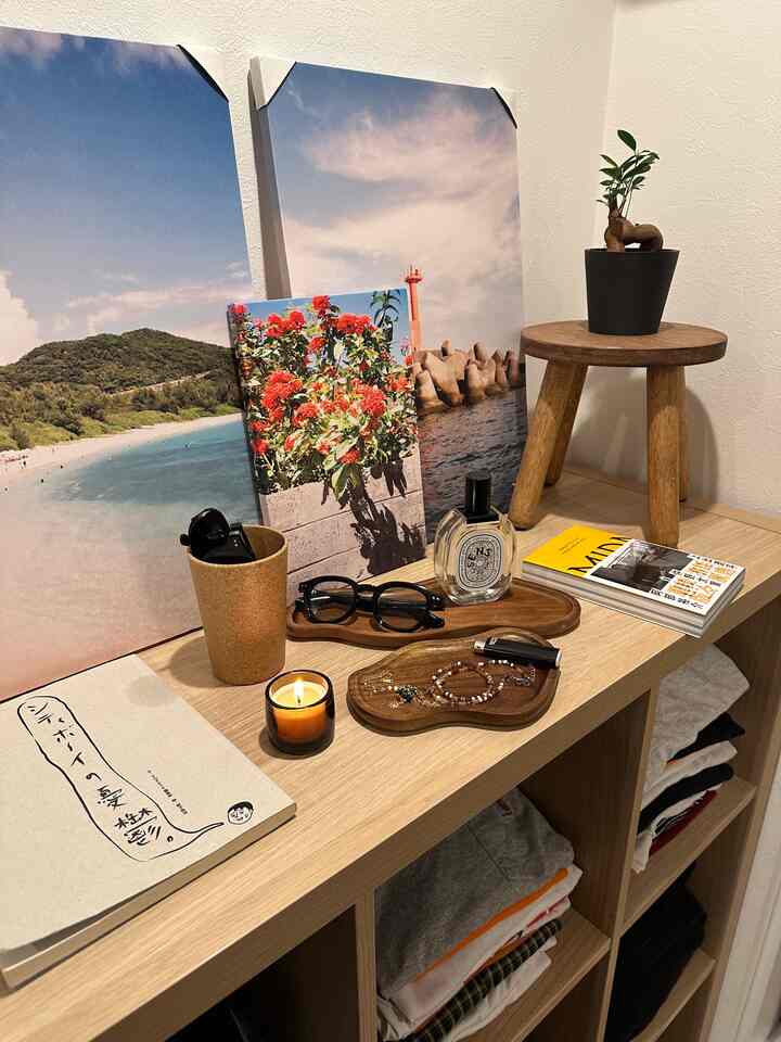 ナチュラルな木目調の玄関スペース、額縁やオブジェ、小さな植物とキャンドルが配置された雰囲気のあるインテリア