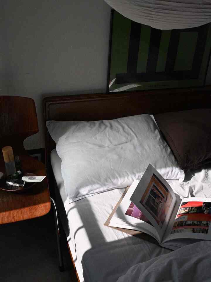 白と茶色のトーンが特徴の寝室、木製のベッドとサイドテーブルが配置された落ち着いたミッドセンチュリーモダンの雰囲気