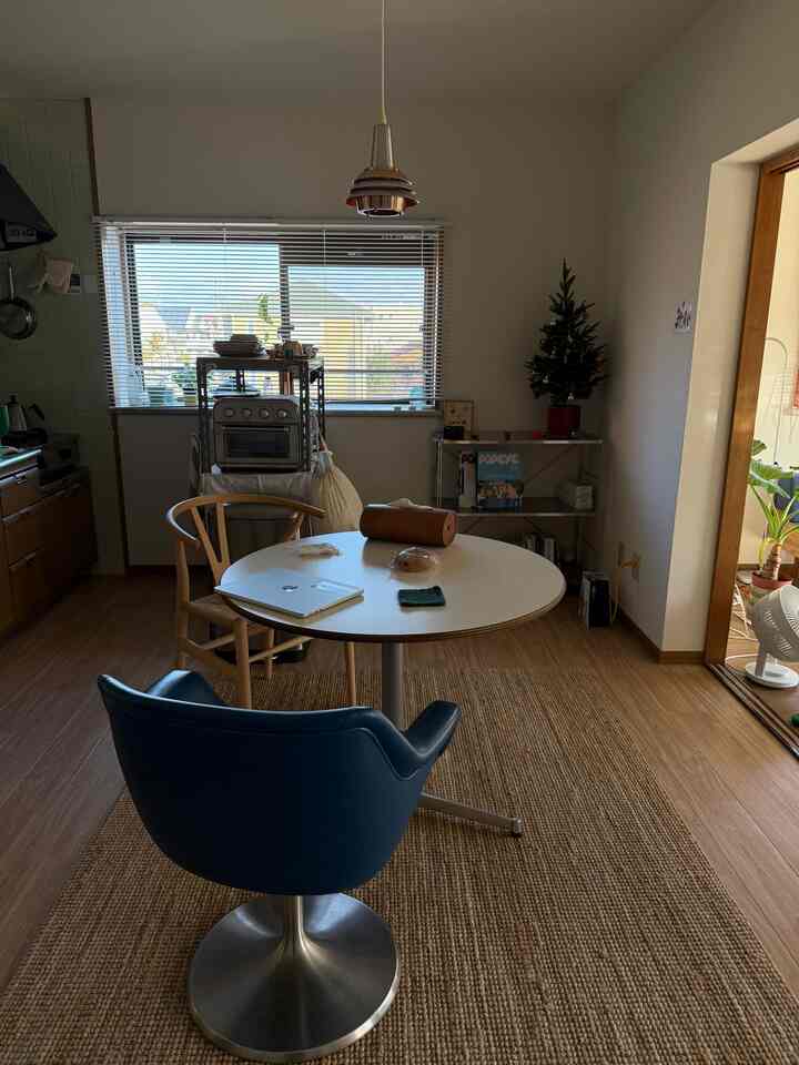 A white and wood-tone 6-tatami dining room featuring a round table and comfortable chairs with a cozy atmosphere