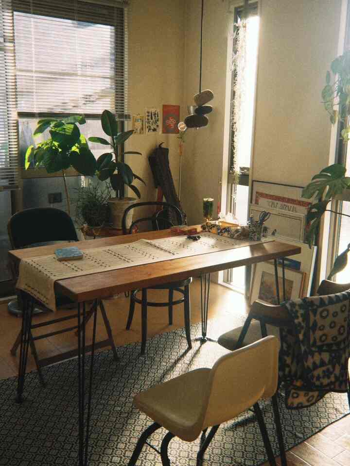 温かみのあるナチュラルカラーと木目調が調和した印象的なダイニング、木製テーブルと多様な椅子、観葉植物が配置された雰囲気のあるインテリア