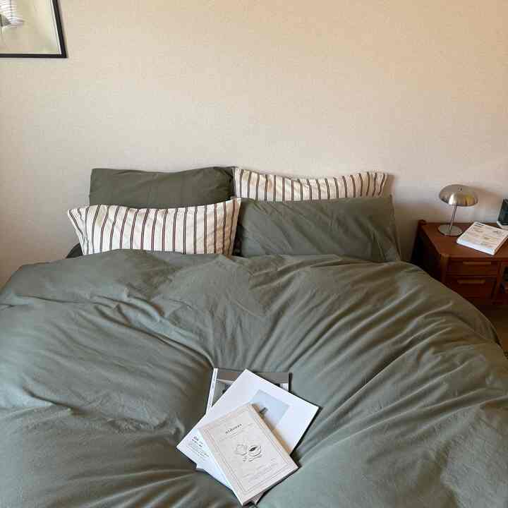 Natural toned bedroom featuring olive green bedding and striped pillows in a cozy atmosphere