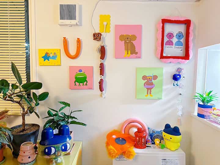 明るくカラフルなリビングの壁、かわいいアートと植物が調和した雰囲気のあるインテリア