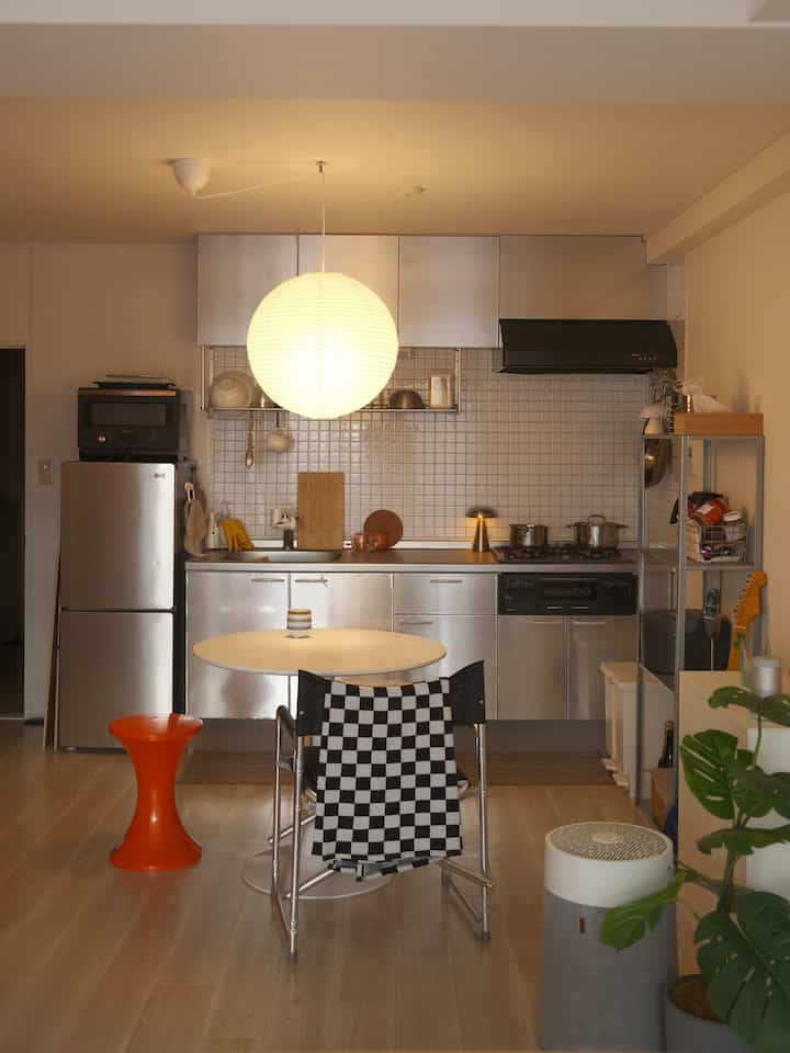 Warm-toned studio kitchen featuring steel cabinetry and white tiled walls in a mid-century modern style