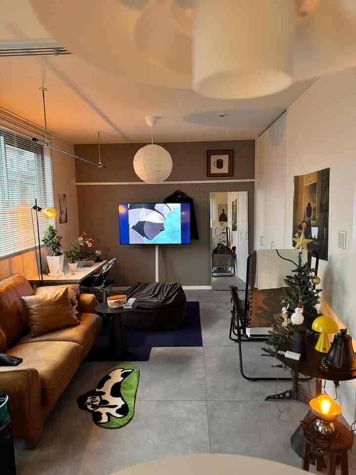 A modern small living room with gray and brown tones featuring a brown leather sofa and bean bag