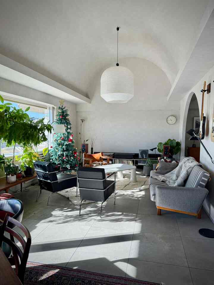 Bright-toned living room featuring Spanish chair and gray sofa in a vintage mid-century modern style interior