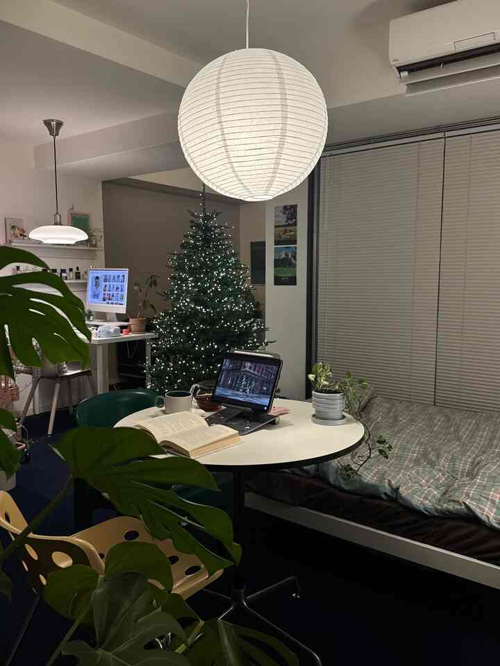 ホワイトとグレーのトーンのワンルームリビング、クリスマスツリーとペンダントライトが配置された雰囲気のあるインテリア