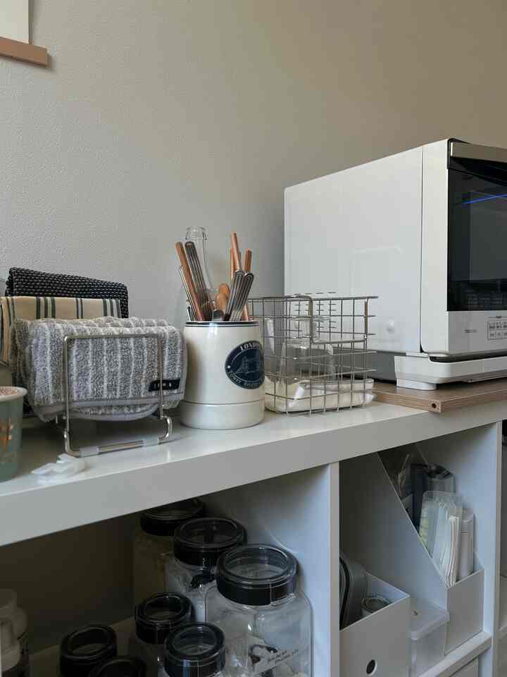 White-toned kitchen space featuring organized storage containers and a microwave with a simple interior design