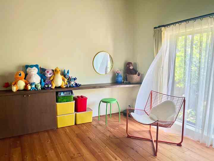 黄色とナチュラルな色調のリビング、カウンターテーブルの上におもちゃが並ぶ落ち着いた空間