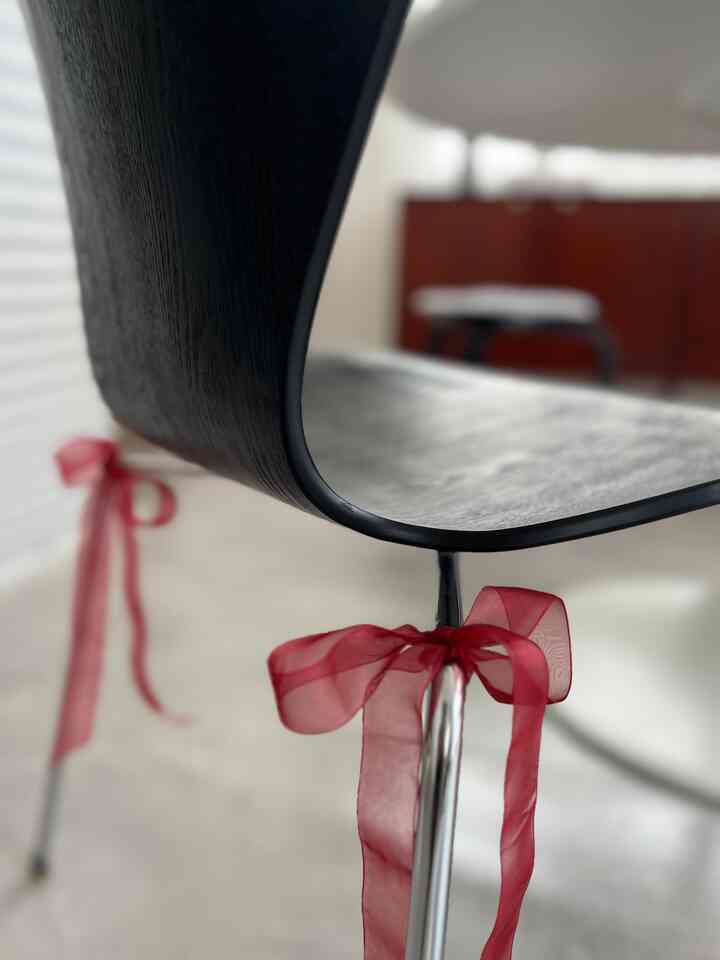 黒いデザイナーズダイニングチェアと赤いリボンが飾られたダイニングの雰囲気あるインテリア
