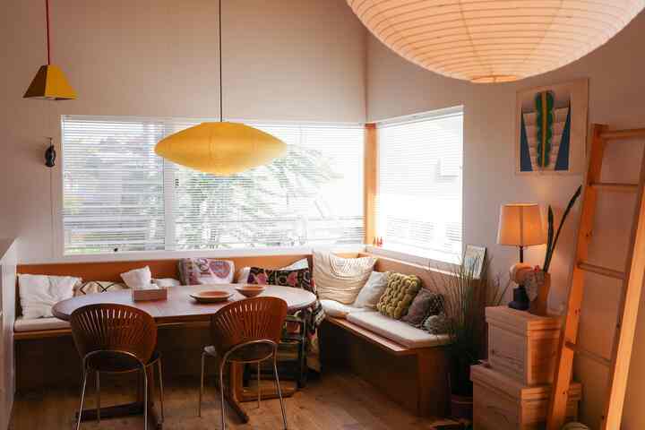 暖かみのある木目調のダイニング、コーナーベンチとダイニングチェア、2つのペンダントライトが配置された雰囲気のある空間