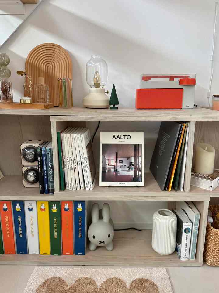 White and beige toned decorative shelf featuring a record player and various interior accessories in a cozy space