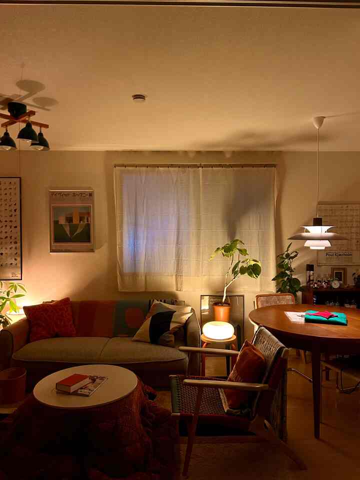 ベージュの背景と木目調家具が調和したミッドセンチュリーモダンスタイルのリビングダイニング空間、ラウンジチェアと植物が落ち着いた雰囲気を演出