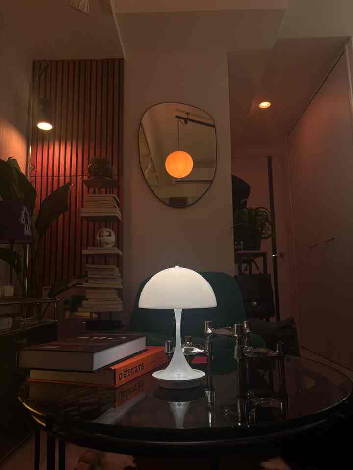 ナチュラルトーンと暖かな照明が調和する1K、8畳のリビング、ルイスポールセンのテーブルランプが配置された雰囲気のある空間