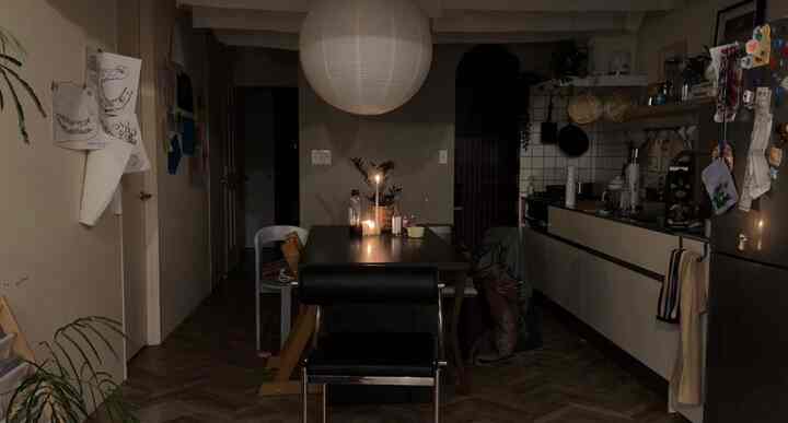 薄暗い照明の下で木目調のダイニングとキッチン、テーブル上にキャンドルが灯る温かみのある雰囲気のインテリア