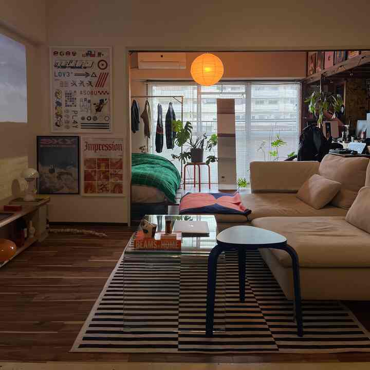 Warm wood tone studio apartment living room with beige sofa and green plants, featuring a cozy mid-century modern style