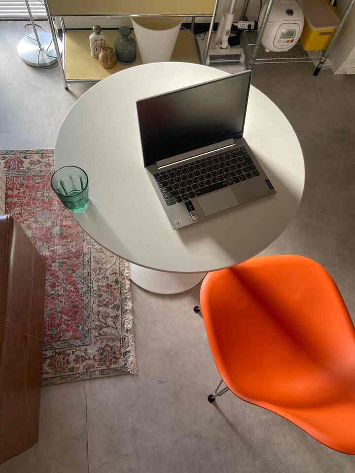 A white and orange toned single household 1DK space featuring a round table and bright chair with a cozy remote work setup