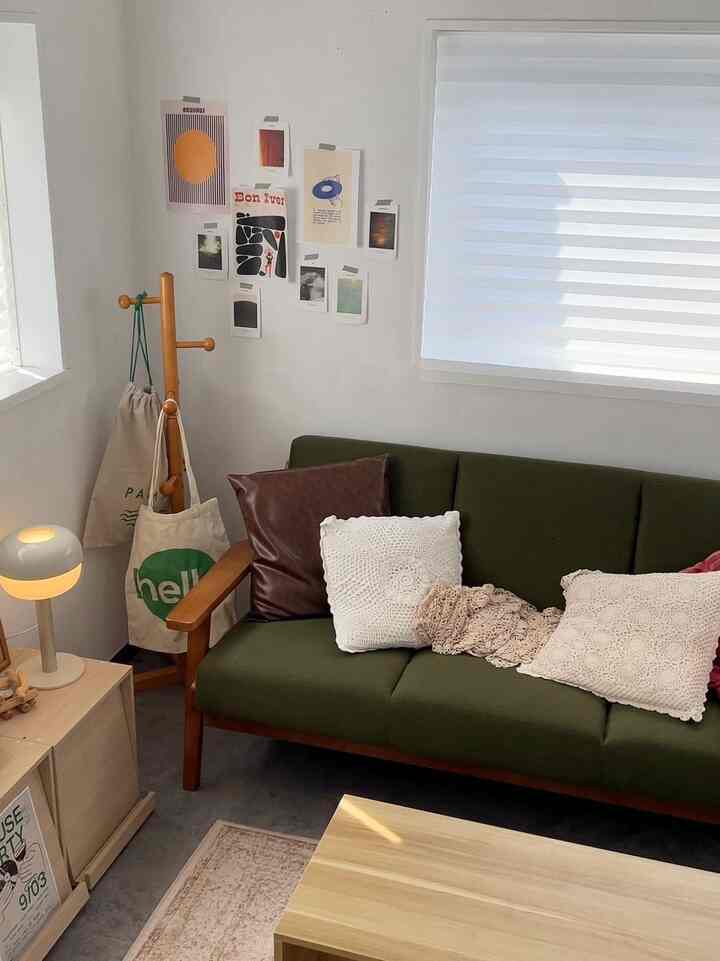 Natural wood-tone cozy living room featuring a green sofa, clean layout, and soft lighting creating a comfortable atmosphere
