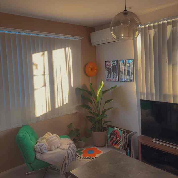 Natural-toned living room with green chair and large plants creating a warm, modern atmosphere