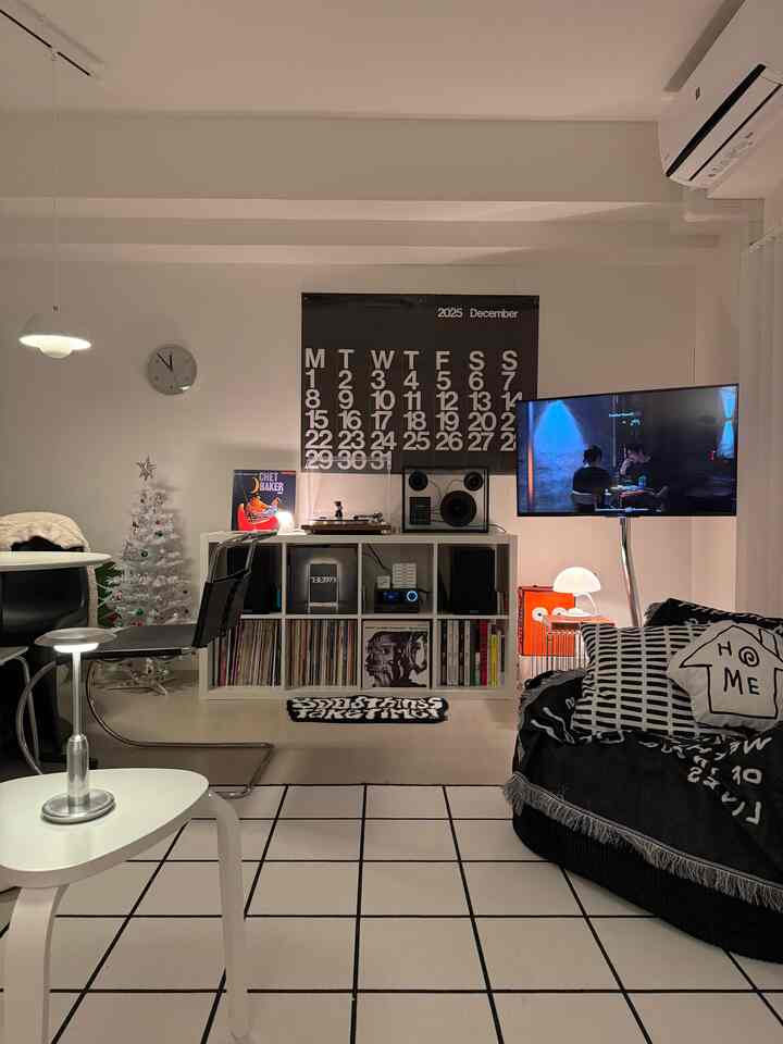 Monotone living room featuring a large rug, sofa, TV, and mid-century modern decor creating a cozy ambiance