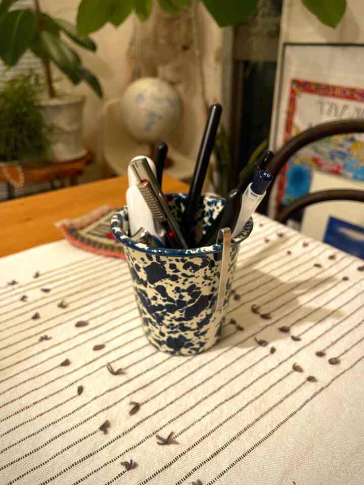 ヴィンテージ風の青い模様のカップにペンが入った、自然な雰囲気の1LDKダイニングテーブルのある印象的な空間