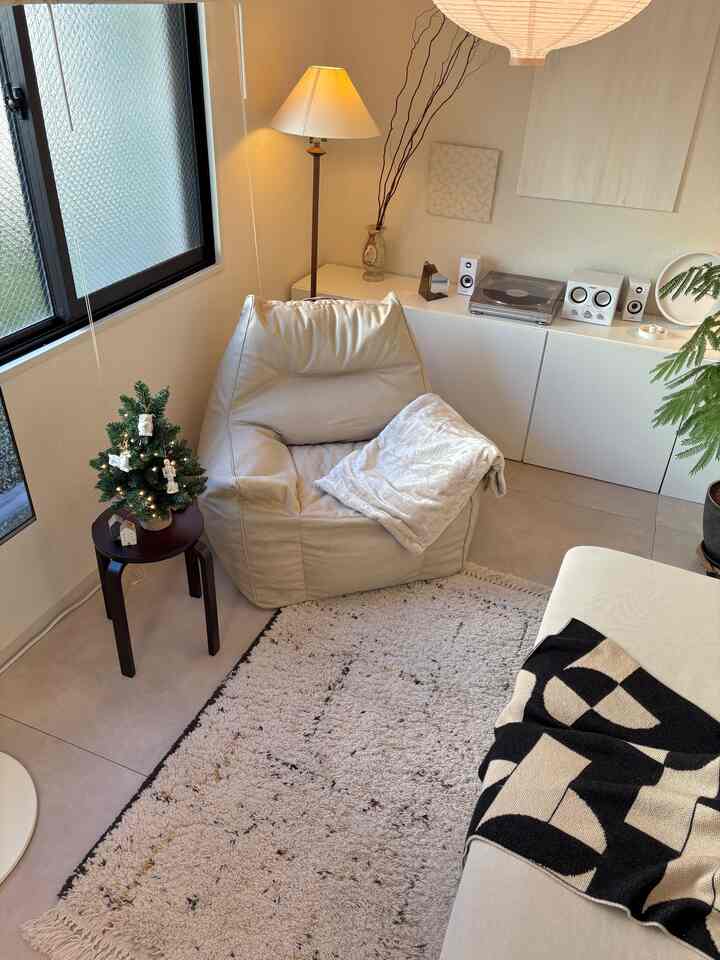 Beige and white toned living room featuring a cozy bean bag, warm floor lamp, and clean natural ambiance