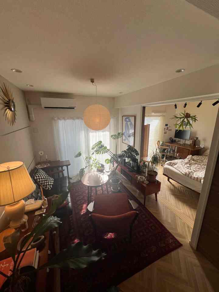 A vintage and mid-century modern Nordic living room with herringbone flooring, featuring various houseplants and warm lighting in a cozy atmosphere