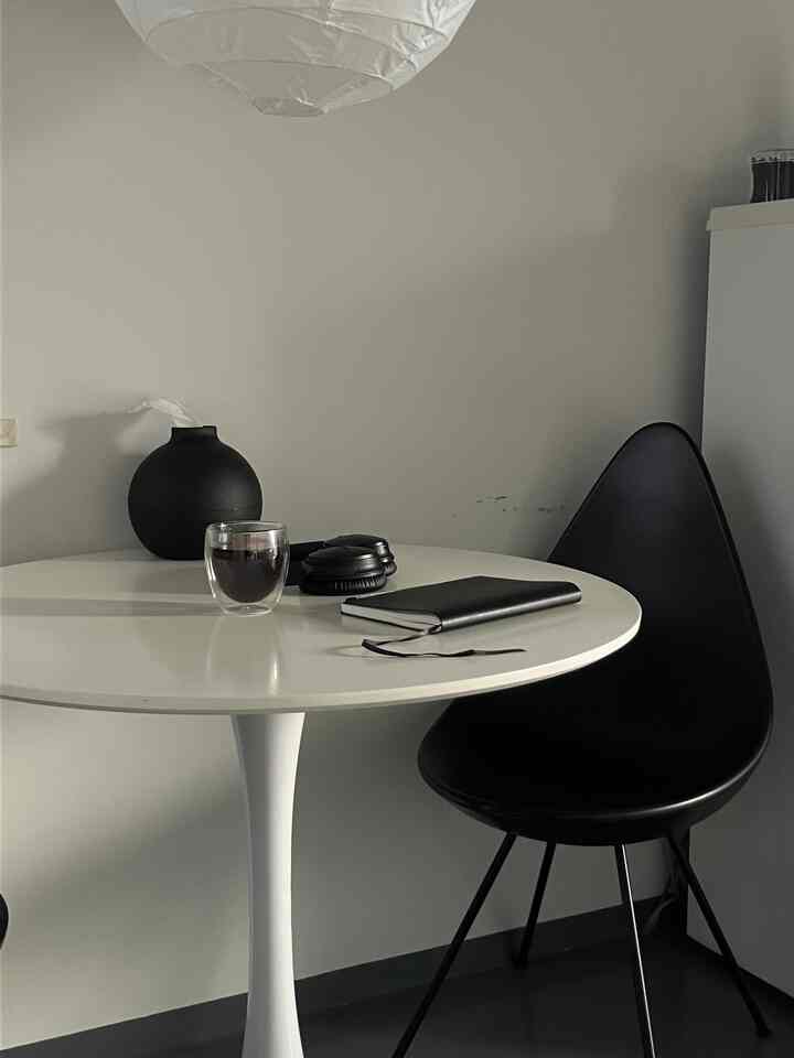 モノトーンの小さなダイニング、白い丸テーブルと黒い椅子が配置されたシンプルな空間