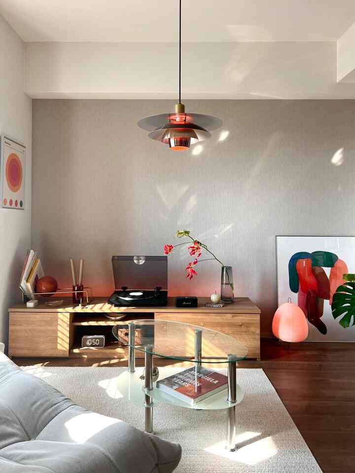 ナチュラルな木目調と白を基調とした一人暮らしのリビング、透明なガラスのサイドテーブルとペンダントライトが調和した空間