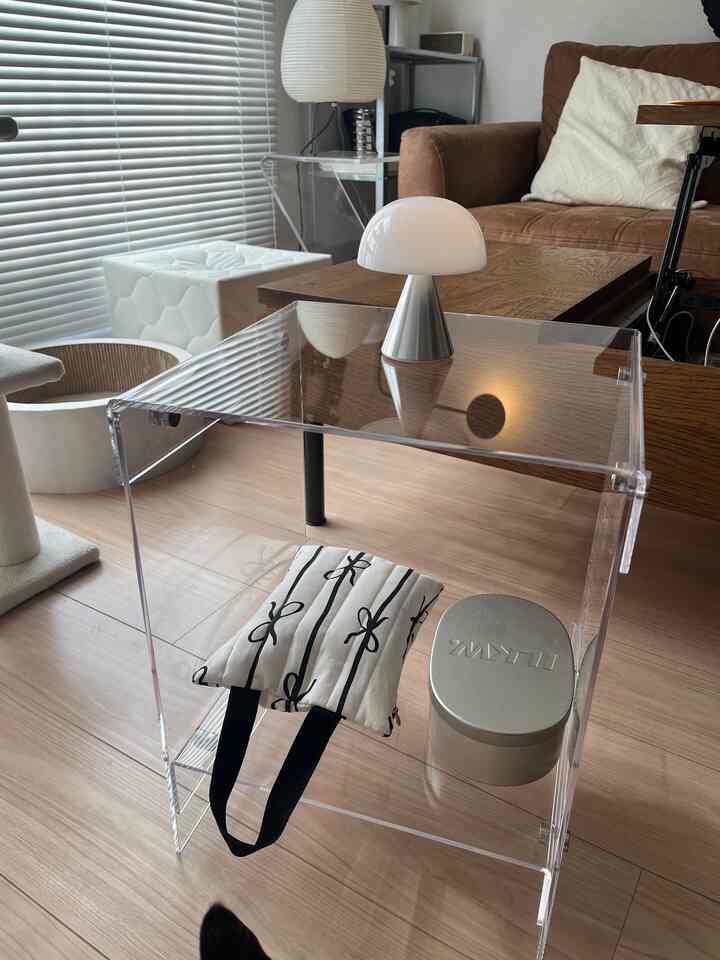 透明なアクリルサイドテーブルとブラウンソファ、白いLEDマッシュルームランプが置かれたミッドセンチュリーモダンのリビング