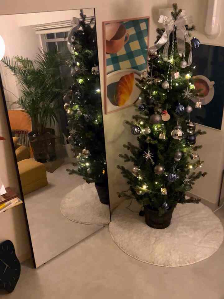 白とグレーの落ち着いた色調のリビング、クリスマスツリーと大型の鏡が配置された雰囲気のある空間