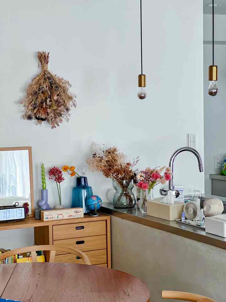 白い壁とブラウンの木製ダイニングテーブルが調和したダイニング、乾燥花とペンダントライトが温かみのある雰囲気を演出