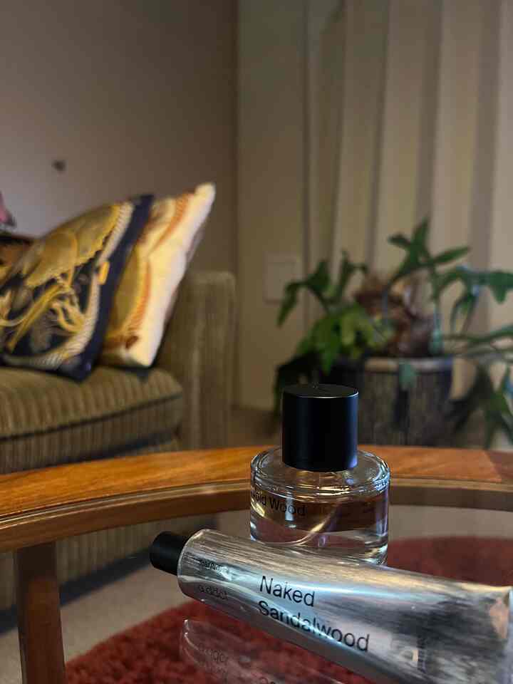 ブラウンのソファと木目調のコーヒーテーブルがあるリビング、キャンドルと植物が配置されて温かみのある雰囲気