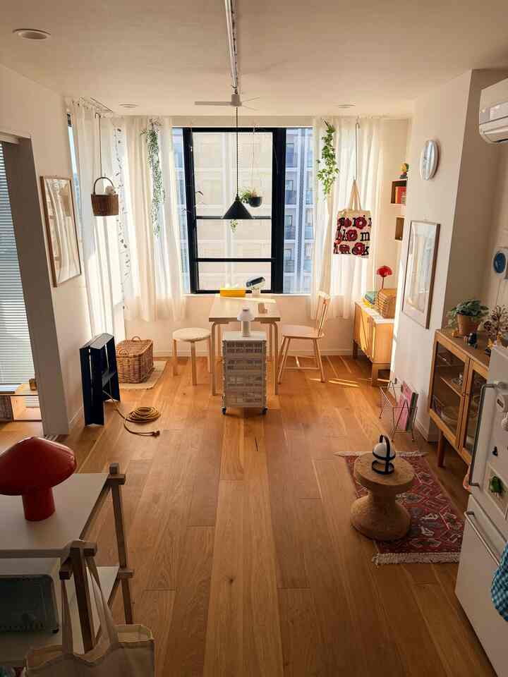 Compact living room with dominant white and wood tones, featuring a small dining table and stools in a cozy interior