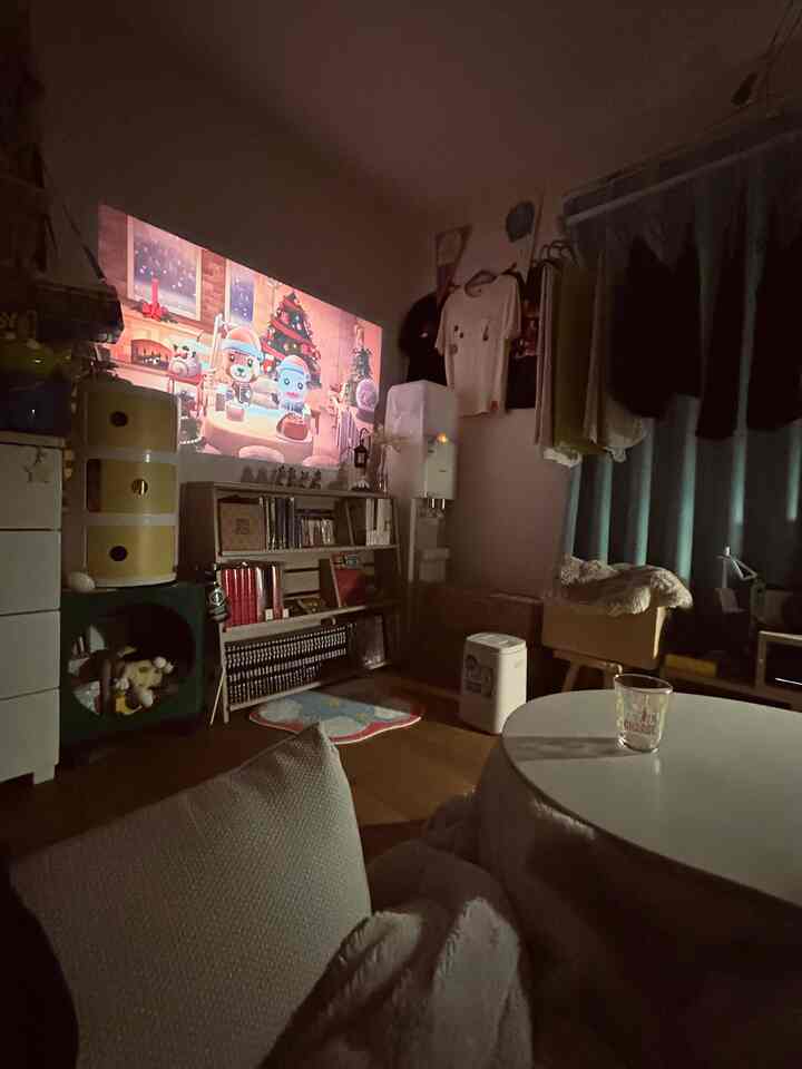 Natural-toned single household living room featuring a kotatsu, recliner sofa, and a cozy projector screen setup